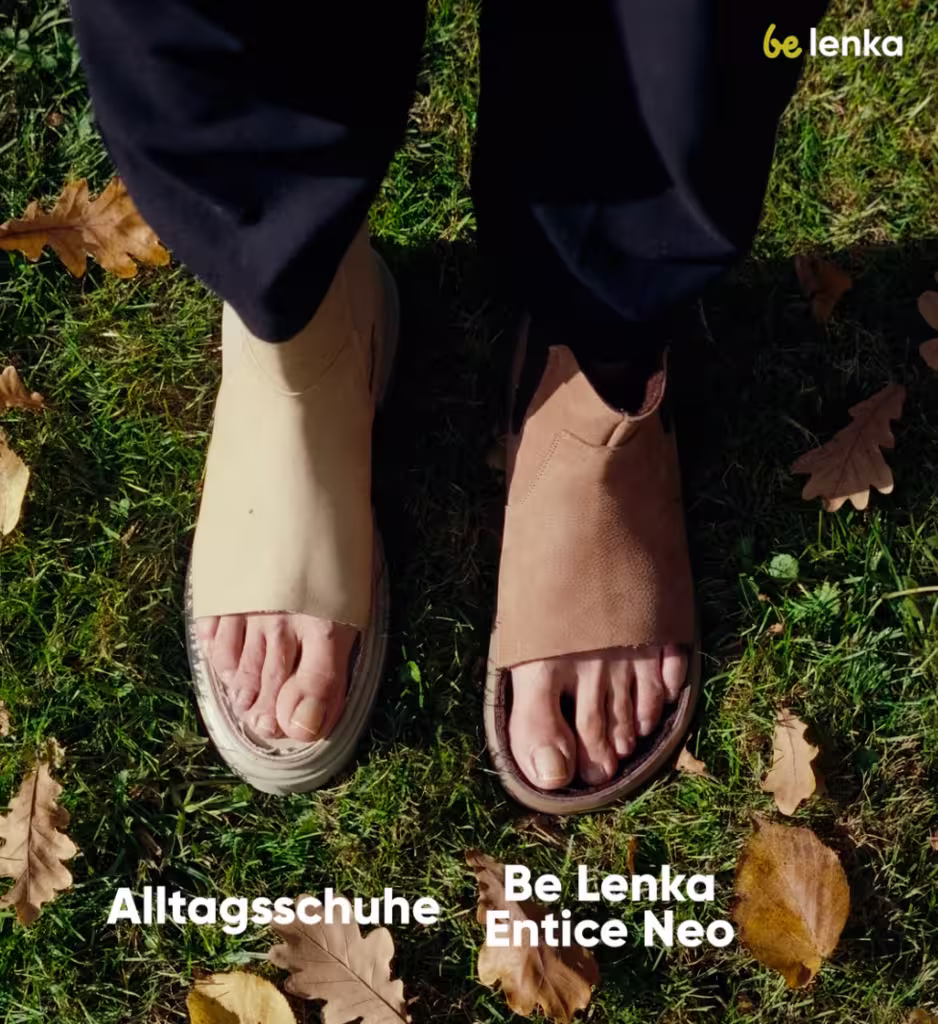Feet wearing beige and brown Be Lenka Entice Neo sandals on grass with autumn leaves.
